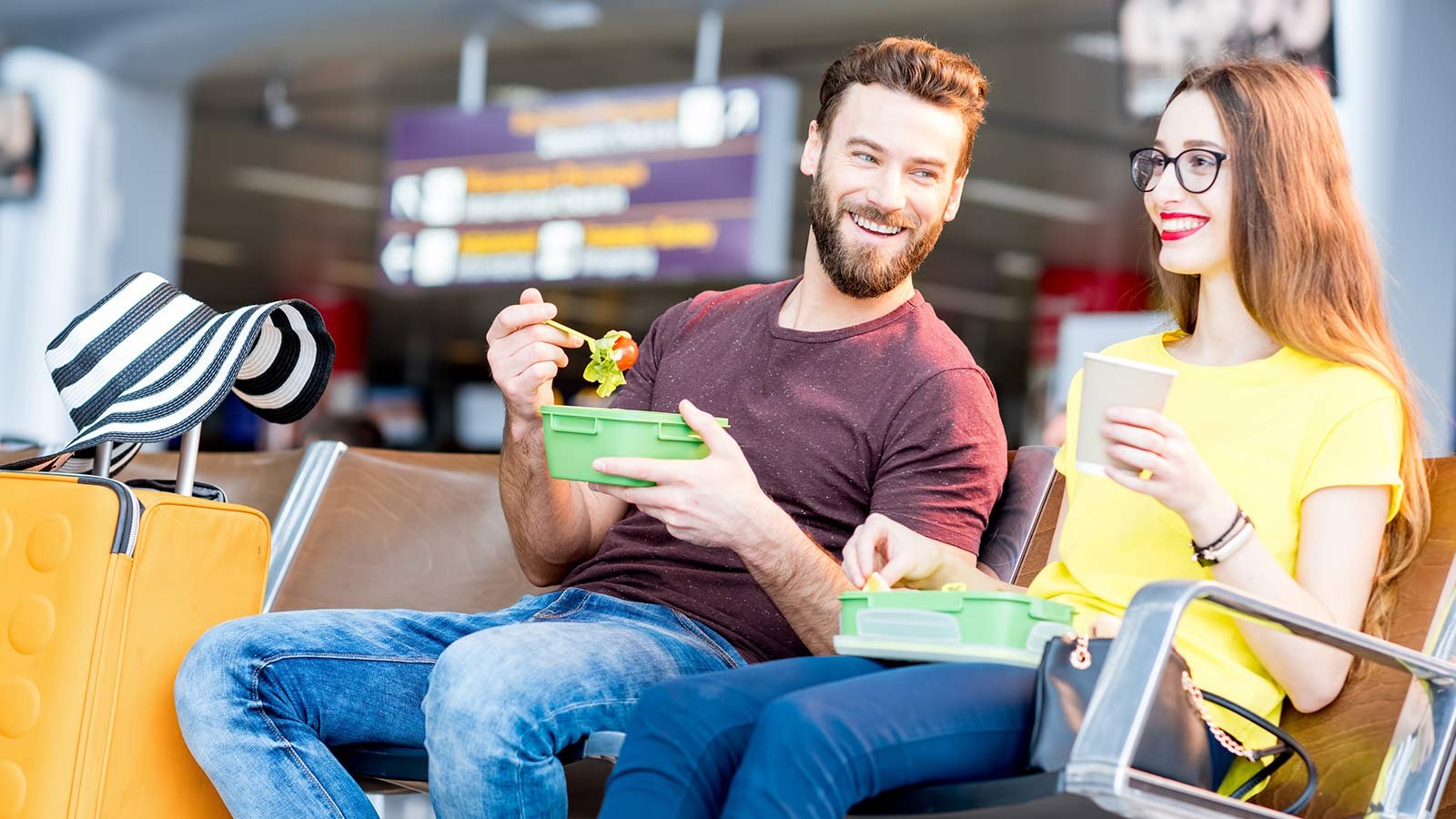 Pareja comiendo ensalada en la terminal del aeropuerto